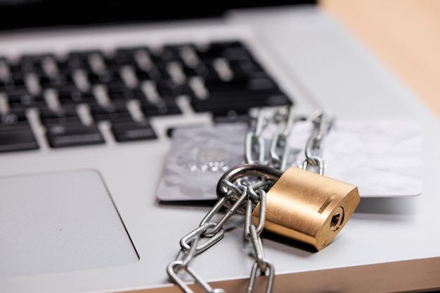 Foto feche de cartão de crédito e laptop com corrente e cadeado.