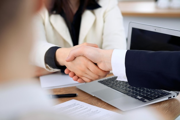 Feche de empresários apertando as mãos na reunião ou negociação no escritório. Os parceiros estão satisfeitos porque assinam contrato.