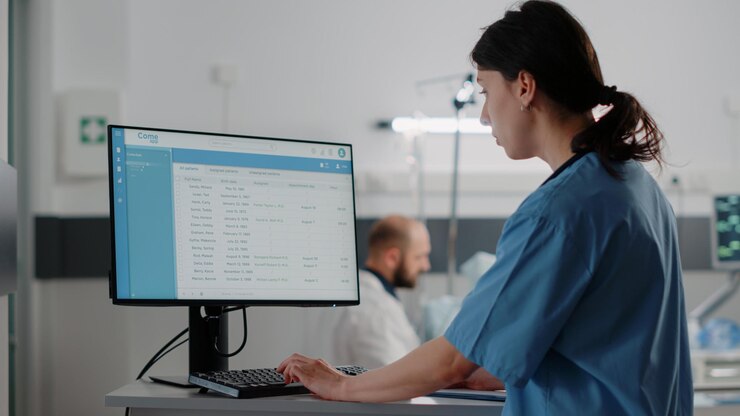 Foto feche de enfermeira mulher trabalhando no computador na enfermaria do hospital. assistente médico digitando no teclado enquanto olha para o monitor com arquivos de saúde para tratamento e recuperação. especialista em saúde