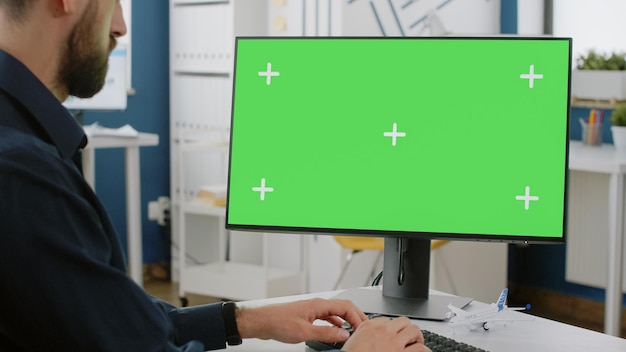 Feche de homem digitando no teclado com tela verde no monitor. Empreendedor de negócios usando computador com chroma key em exibição para fundo isolado horizontal e modelo de maquete