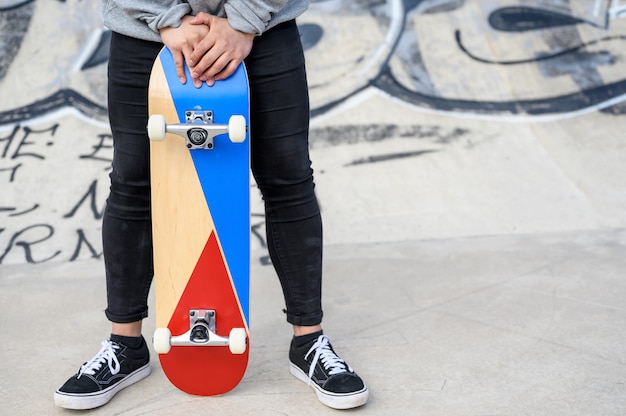 Foto feche de jovem irreconhecível segurando longboard ou skate no parque.