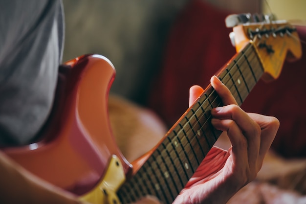 Feche de mãos masculinas tocando guitarra elétrica. Foco seletivo