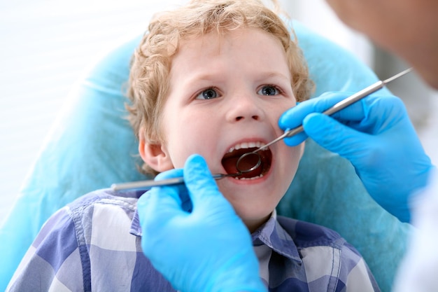 Feche de menino tendo seus dentes examinados por um dentista.