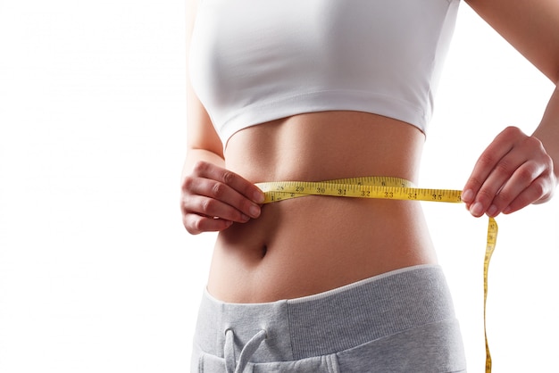 Foto feche de mulher magro, medindo o tamanho da cintura com fita métrica.