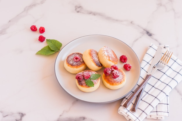 Feche de panquecas de queijo cottage com frutas frescas na mesa de mármore branco. Comida saborosa para o café da manhã. Syrniki