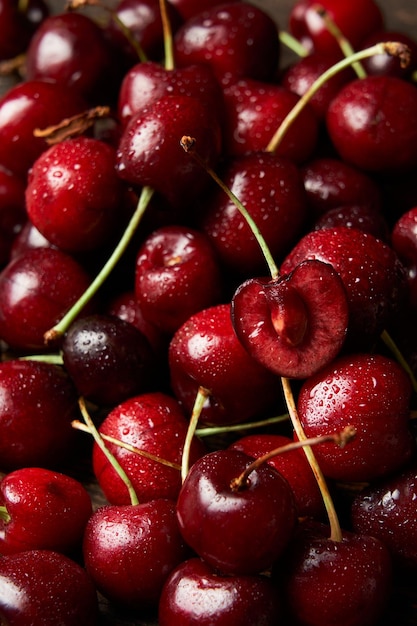 Foto feche de pilha de cerejas vermelhas doces com caules e folhas. fundo de cerejas. comida vegana