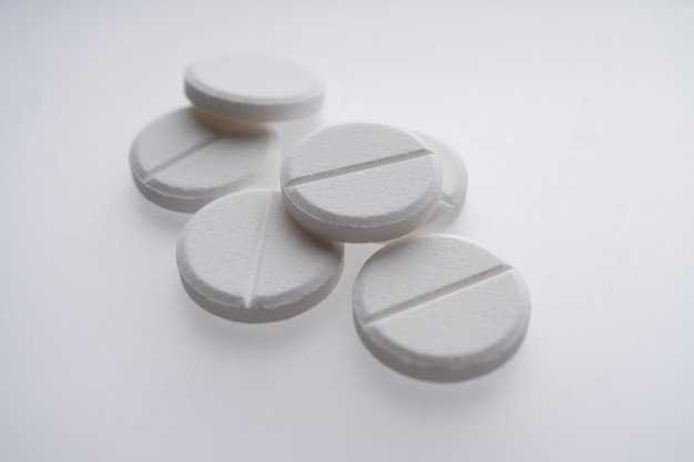 Feche de pílulas brancas sobre fundo branco, medicina e conceito de saúde
