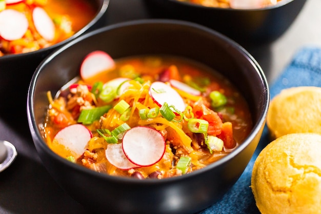 Feche de pimentão de peru guarnecido com rabanetes frescos, cebolinha e queijo cheddar.