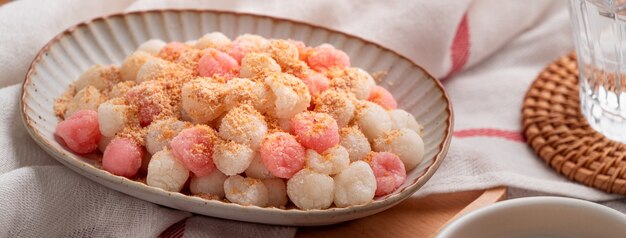 Feche de tangyuan vermelho e branco frito (tang yuan, bolinhas de massa de arroz glutinosas) com pó de amendoim no fundo da mesa cinza para comida do festival do solstício de inverno.