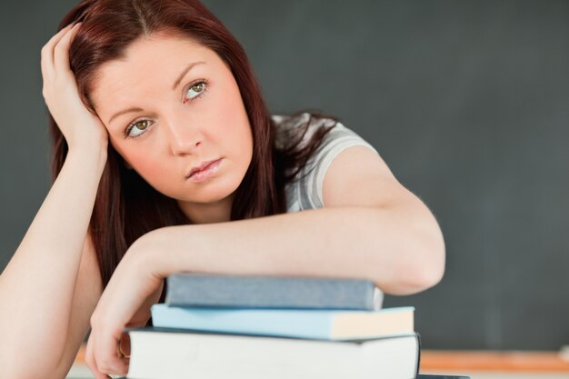 Feche de um belo estudante entediado com o antebraço em seus livros