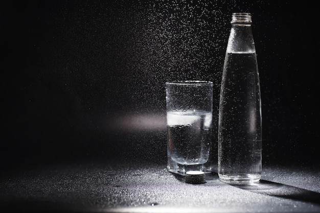 Feche derramando água purificada da garrafa na mesa na sala de estar. Água potável. Água com vitaminas minerais. Água saudável, rica em minerais e refrescante.
