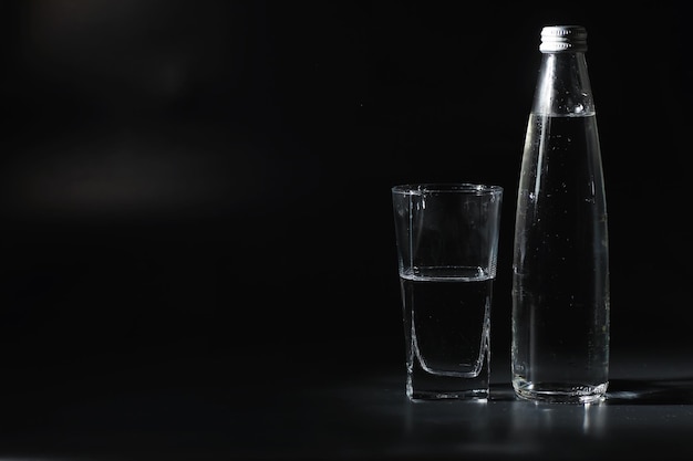 Feche despejando água purificada da garrafa na mesa na sala de estar. Água potável. Água mineral com vitaminas. Água saudável, rica em minerais e refrescante.