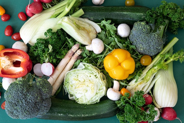 Feche diferentes vegetais brilhantes em um plano de fundo verde