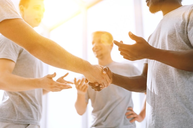 Feche dois camaradas apertando as mãos em um círculo de amigos