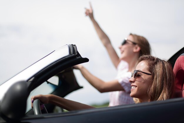 Feche duas jovens viajando em um estilo de vida elegante de carro conversível