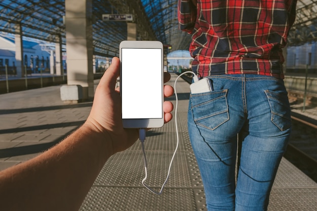 Feche em um celular em branco com o banco de energia na mão