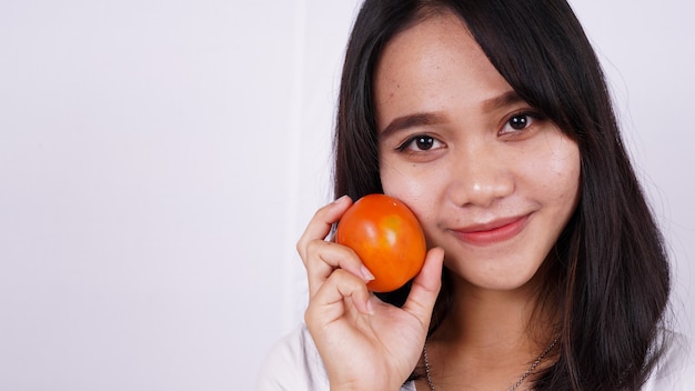 Feche lindas mulheres asiáticas com um tomate isolado na superfície branca