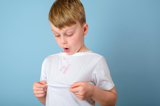 Feche manchas sujas de sorvete em uma camiseta infantil em um fundo azul