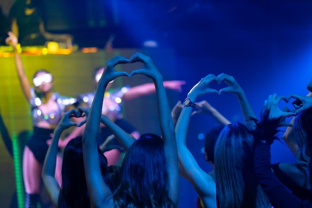 Foto feche o amor de mão ou mini coração vida noturna e conceito de festa de dança discoteca mulher sexy pessoas e amigos dançando no festival de música de boate alegre feliz diversão pessoas asiáticas dançam em boate