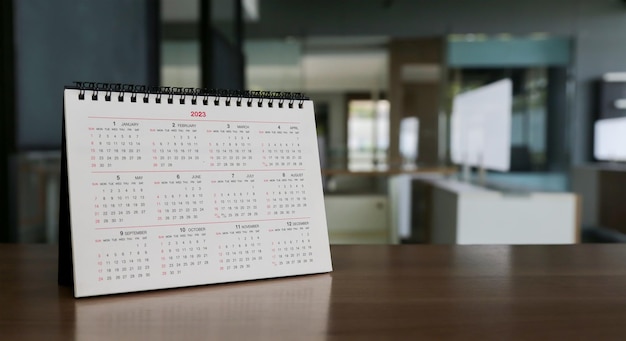 Feche o calendário branco em ideias de planejamento de mesa de escritório marrom