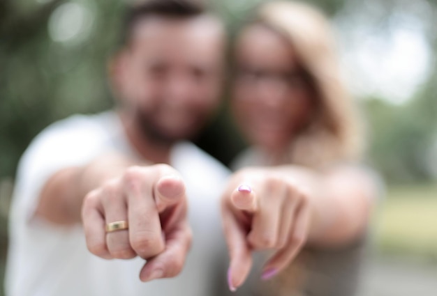 Feche o casal feliz parado no parque e apontando para você