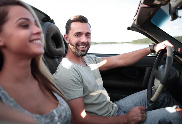 Feche o casal sentado em um carro conversível