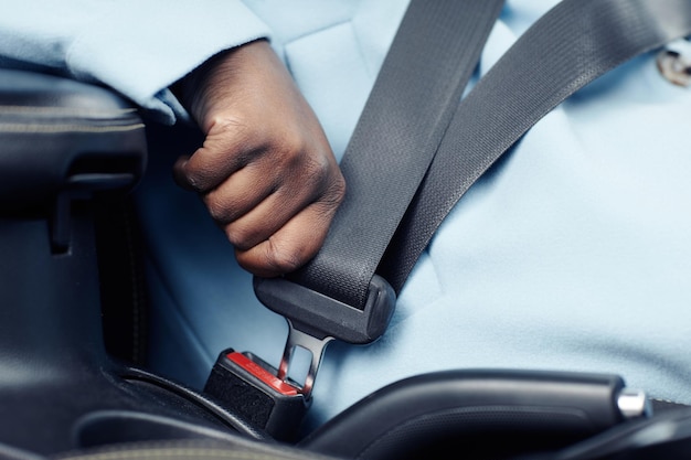 Foto feche o cinto de segurança em jejum de mulher negra irreconhecível no espaço de cópia do carro