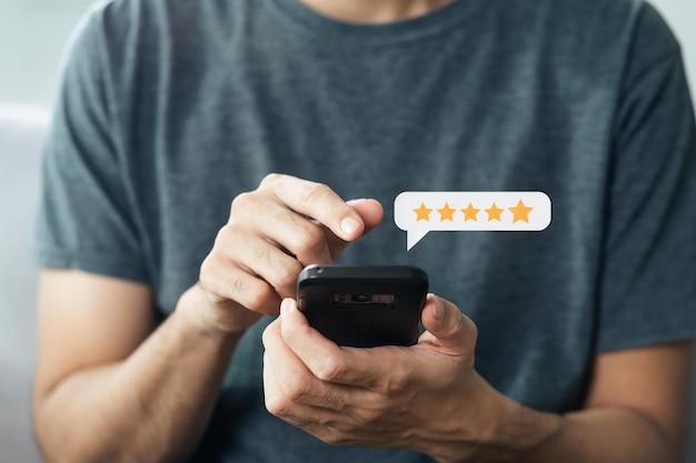 Feche o cliente homem dando uma classificação de cinco estrelas no smartphone. Revisão, classificação de serviço, satisfação, experiência de atendimento ao cliente e conceito de pesquisa de satisfação.