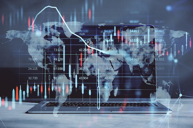 Feche o computador portátil com gráfico forex de velas brilhantes e holograma de mapa em fundo desfocado Mercado de investimento de ações e conceito de dinheiro Dupla exposição