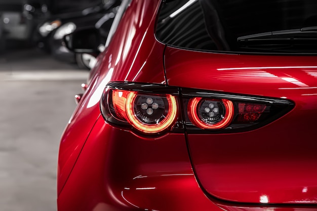 Feche o detalhe em um dos carros modernos de cruzamento vermelho da lanterna traseira vermelha. Detalhe automóvel exterior.