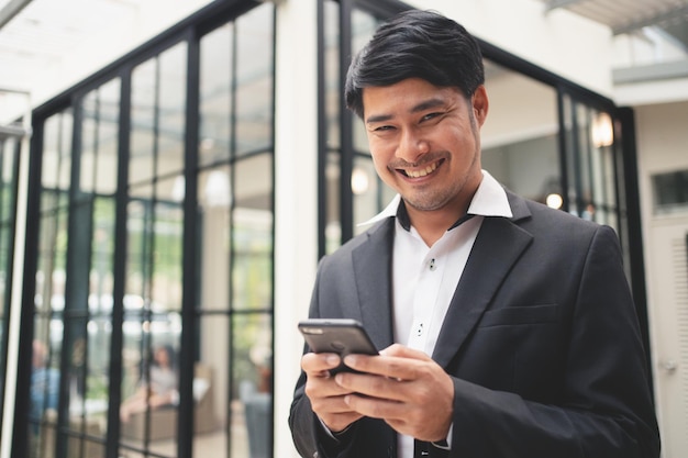 Feche o empresário digitando no telefone inteligente e sorrindo