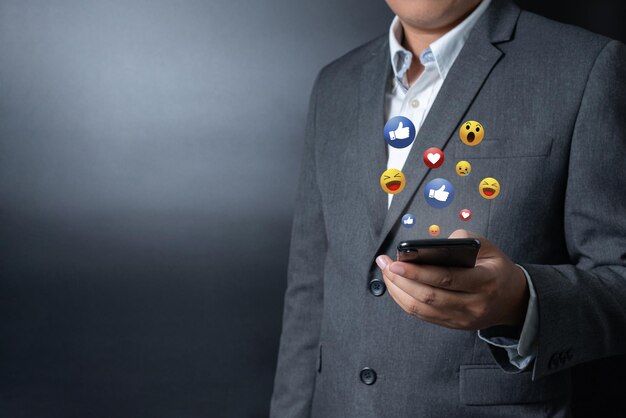 Foto feche o empresário empurrando o toque no smartphone com o ícone de emoção virtual em fundo preto