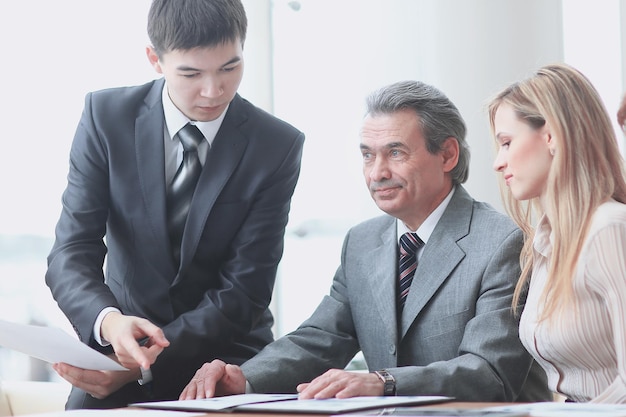 Feche o gerente de projeto e a equipe de negócios em uma mesa no escritório