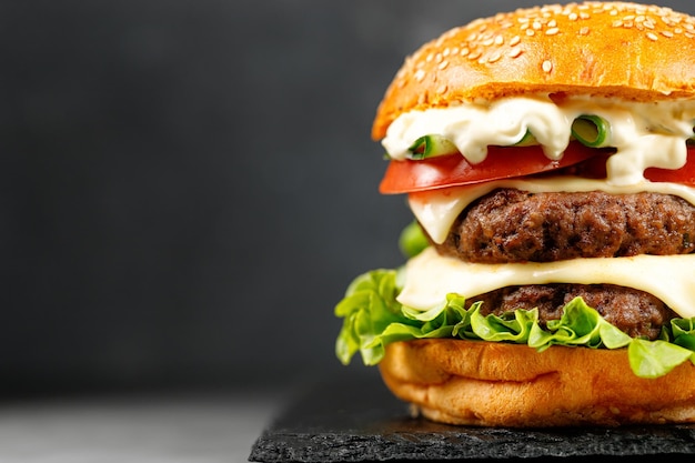 Feche o hambúrguer com costeletas de carne Alface de pepino de queijo em fundo preto Restaurante Fast Food