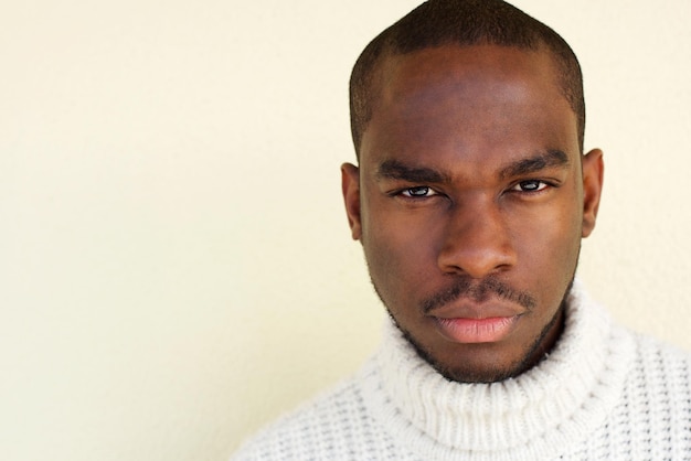 Feche o homem africano bonito com suéter na parede