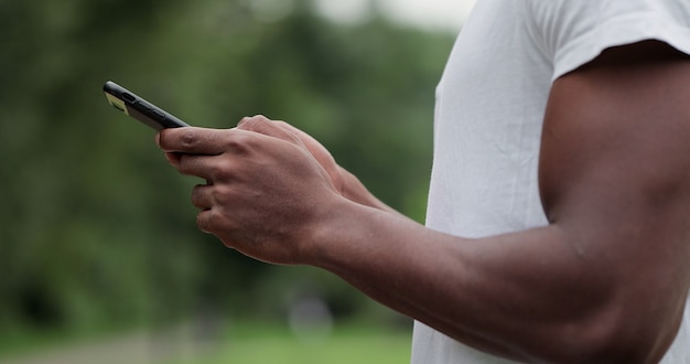 Feche o homem afro-americano do atleta ativo olhando para o aplicativo do smartphone após o treino cardiovascular para obter informações e dados de ritmo, distância e frequência cardíaca.