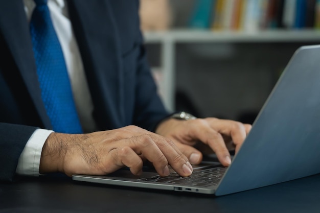 Feche o homem de negócios da mão vestindo terno digitando e trabalhando no computador portátil na mesa de madeira no escritório em casa Homem empresário trabalhando para negócios no escritório em casa Conceito de tecnologia de trabalho