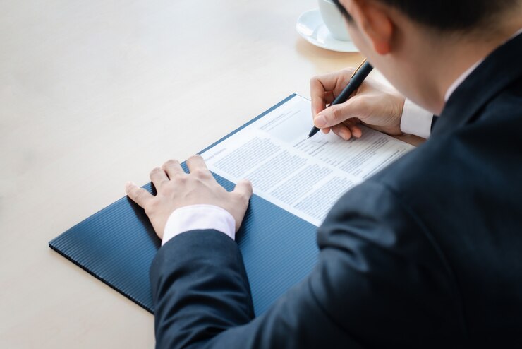 Feche o homem de negócios, escrevendo ou assinando contrato em papel no escritório.