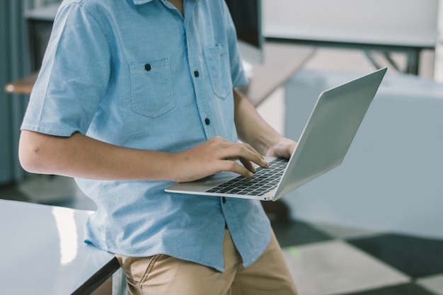 Feche o homem estudante sentado e usando o laptop na classe