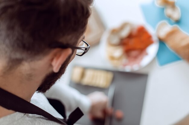 Feche o homem fazendo sanduíches na cozinha