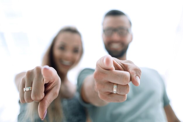 Feche o jovem casal apontando para você