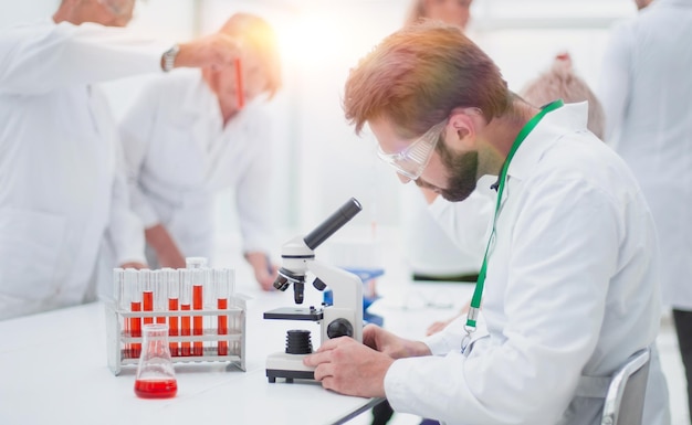 Feche o jovem cientista sentado em uma mesa no laboratório