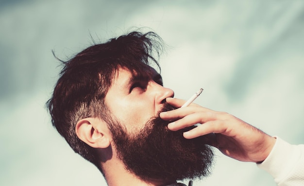 Feche o jovem fumando um cigarro