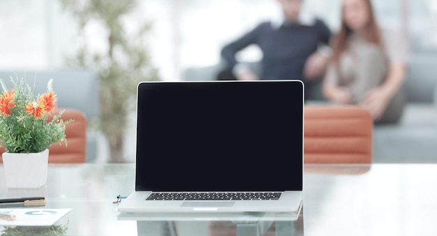 Feche o laptop aberto em uma mesa de vidro no escritório