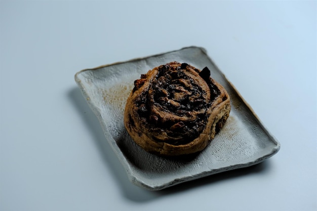 Feche o pão de rolo de canela e passas no fundo branco Roti