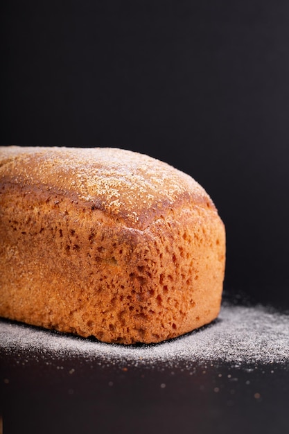 Feche o pão francês magro com farinha em um fundo preto Receita de conceito de pão artesanal