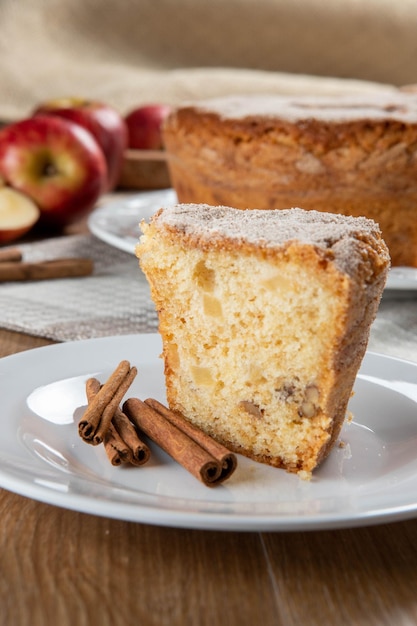 Feche o pedaço de bolo de esponja ou bolo de chiffon com maçãs tão macias e deliciosas fatiadas com ingredientes ovos de canela farinha de maçãs na mesa de madeira Conceito de padaria em casa para plano de fundo e papel de parede