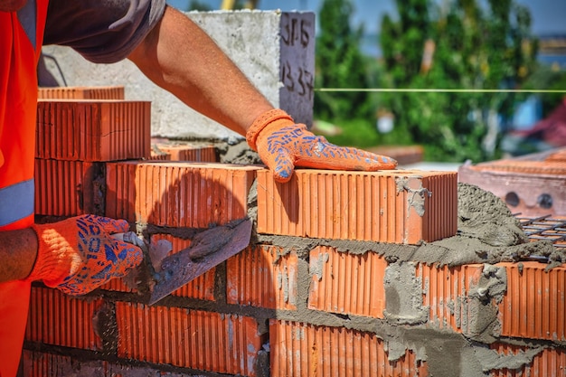 Feche o pedreiro industrial instalando tijolos no trabalhador do canteiro de obras com tijolos