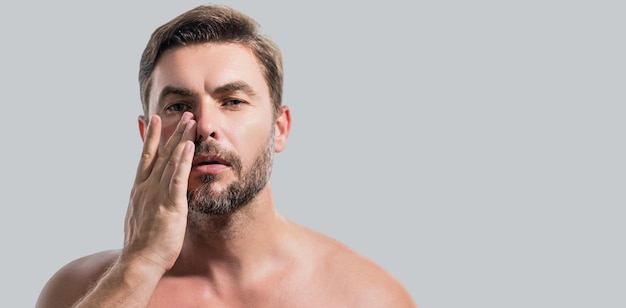 Feche o retrato da beleza de um homem satisfeito após o creme facial, um moreno atraente, tocando a pele dos homens