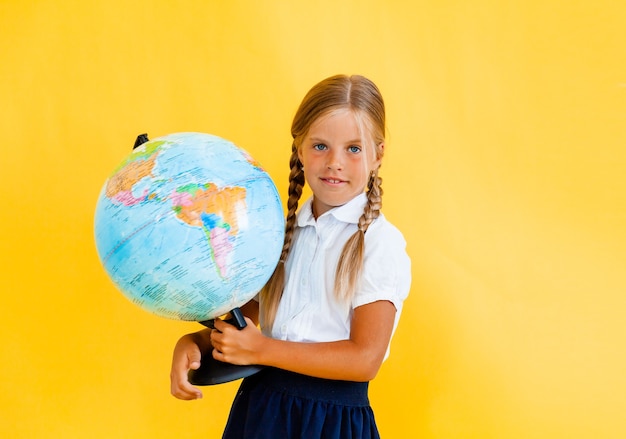 Feche o retrato da foto de uma garota engraçada e fofa surpresa segurando o globo nas mãos